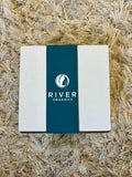 White box with a blue River Organics label on a textured beige surface