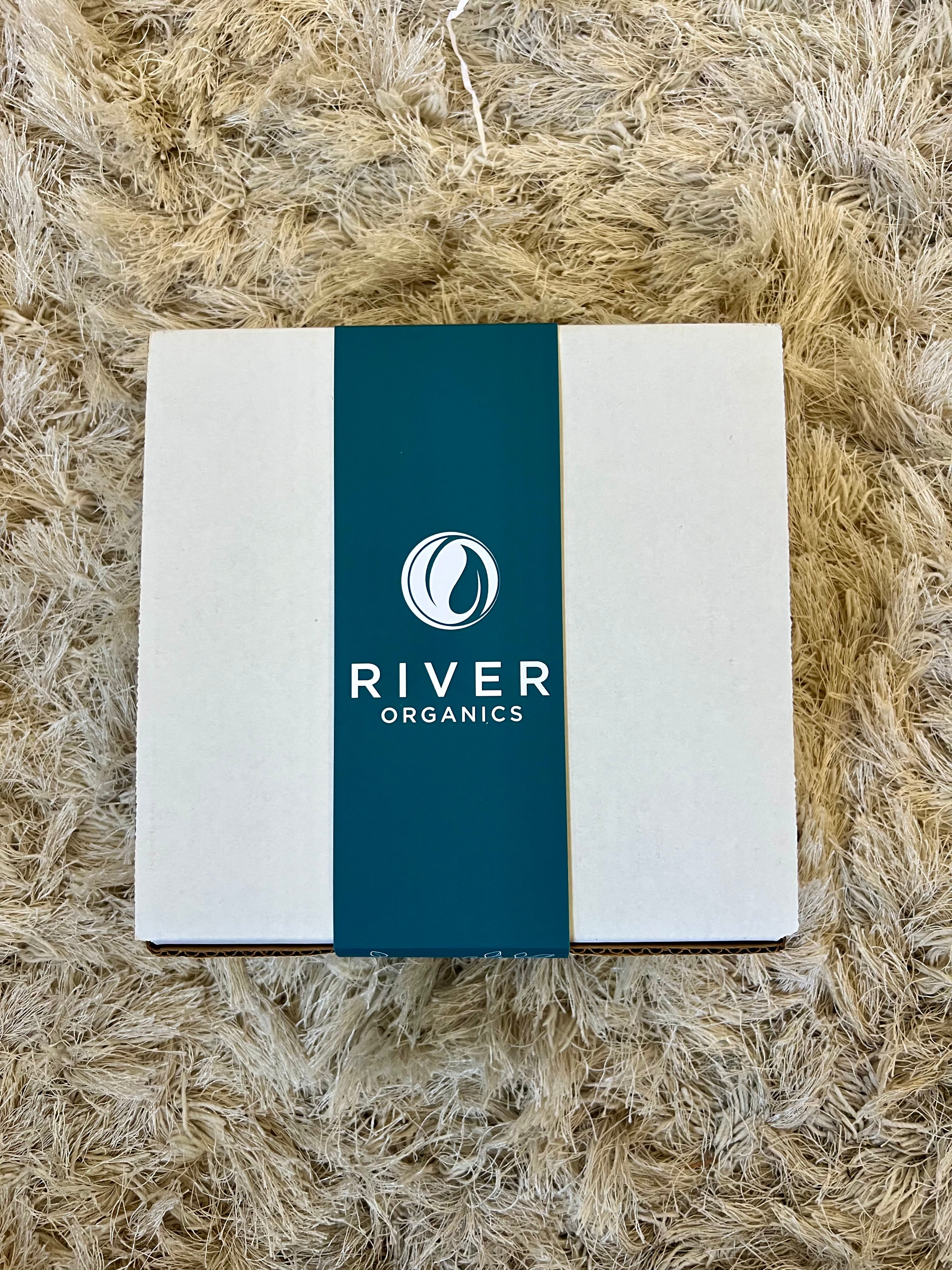 White box with a blue River Organics label on a textured beige surface