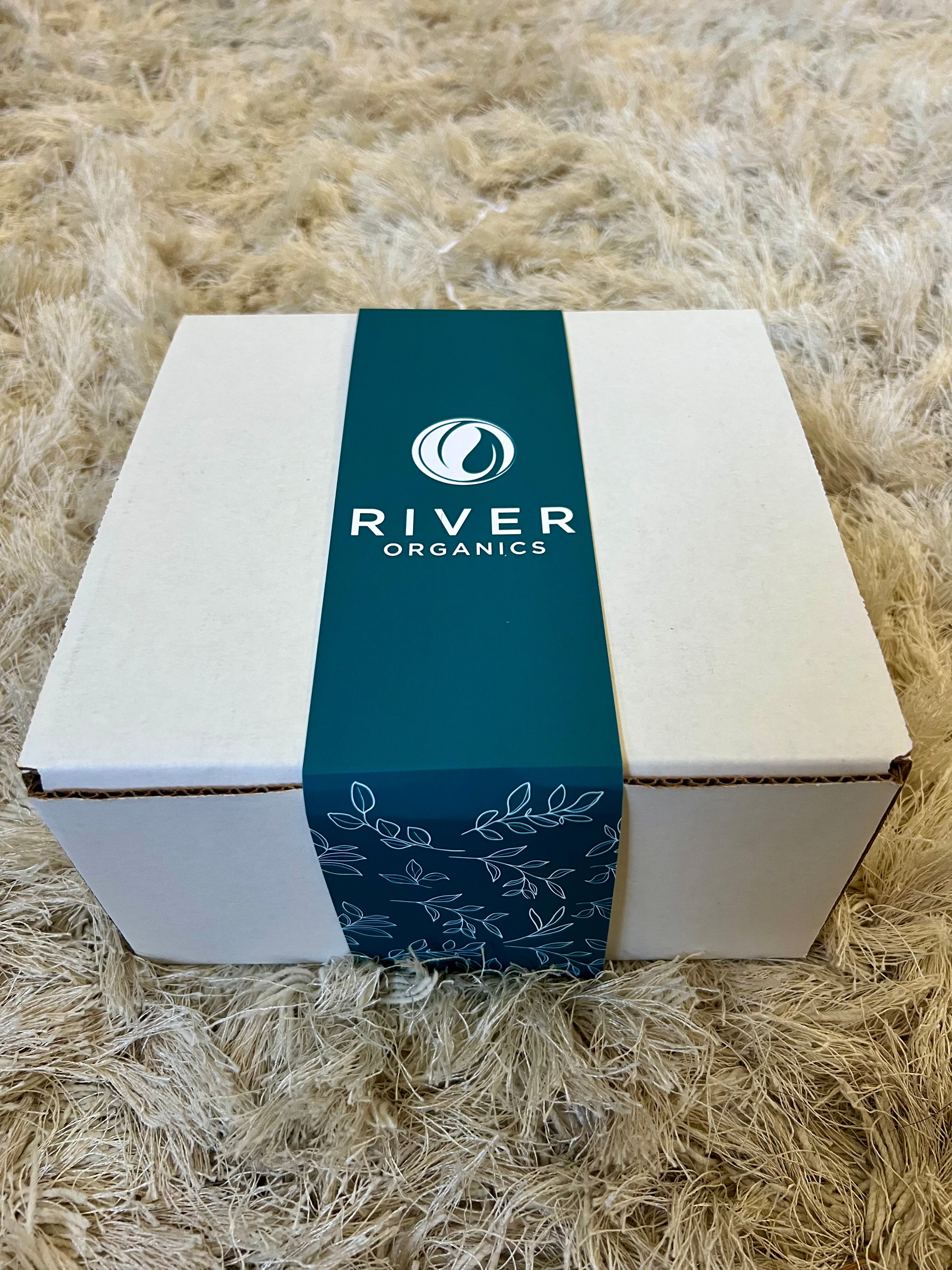 White box with a blue River Organics label on a textured beige surface