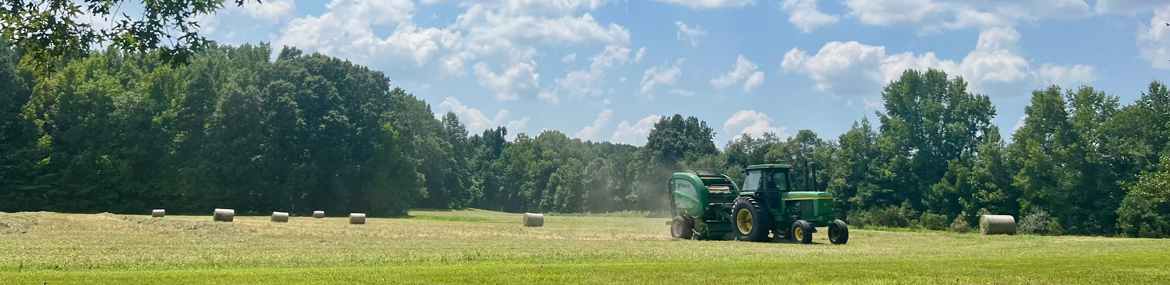 Tractor in a field with trees and blue sky